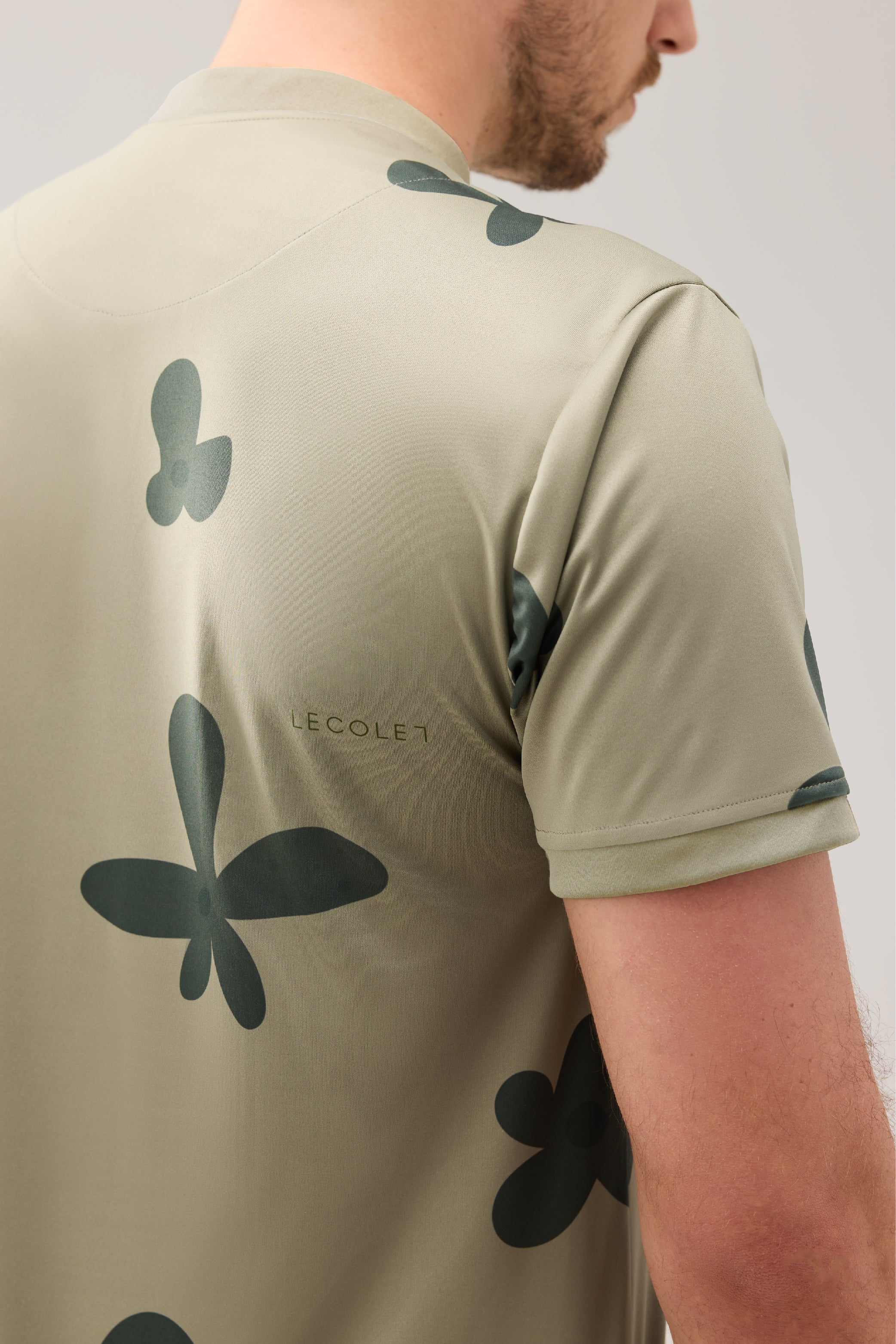 Lecolet SEED golf polo Green blossom. Green golf polo with darker flower design. Detail dark green below right scapula.